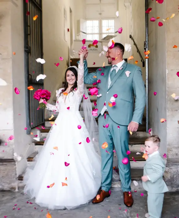Lancer de pétales sur les mariés et l'enfant d'honneur à la sortie de cérémonie, un moment de joie immortalisé par votre vidéaste mariage