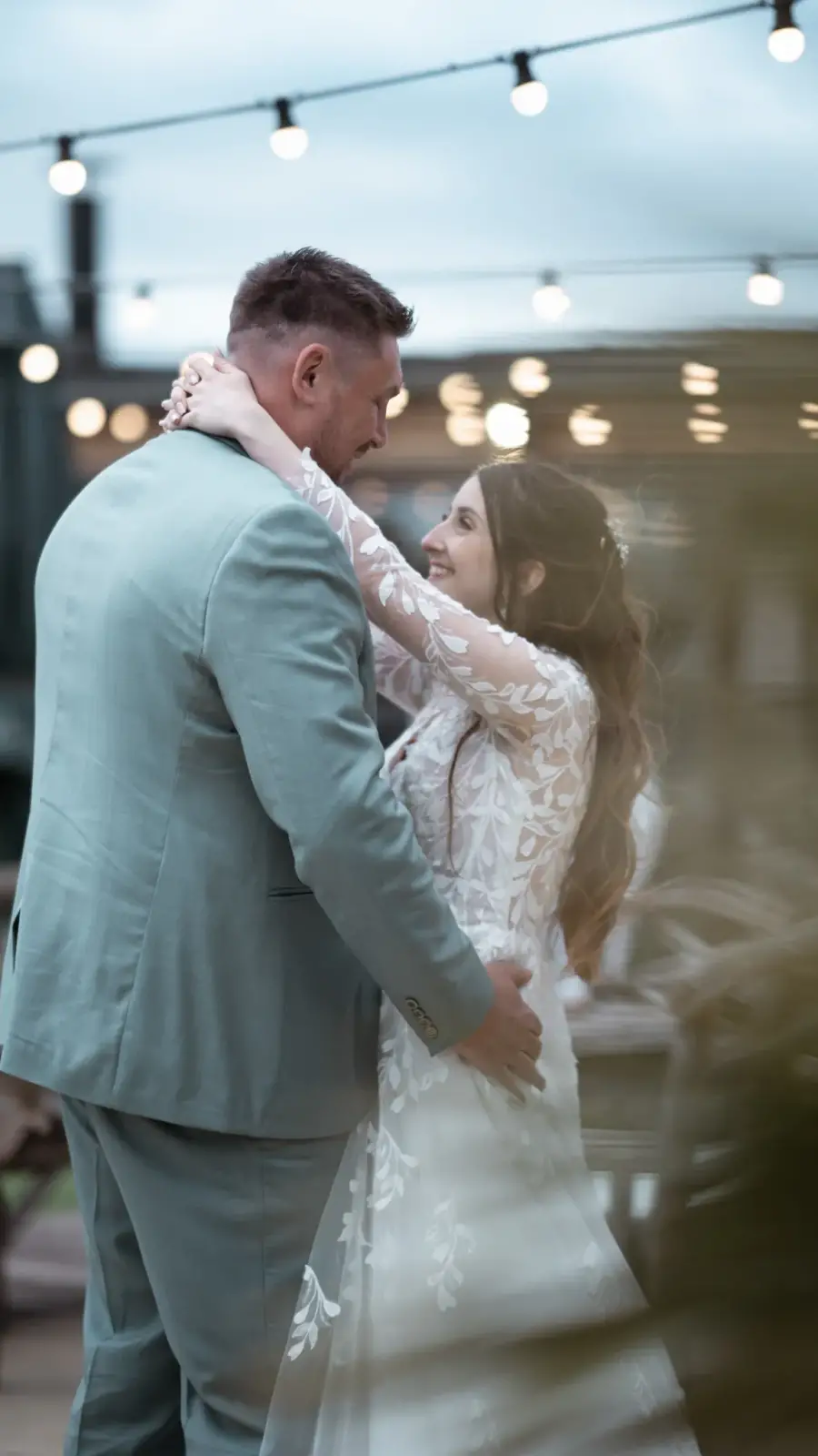 Danse romantique des mariés sous des guirlandes lumineuses, ambiance de soirée capturée par votre photographe et vidéaste de mariage en Provence.