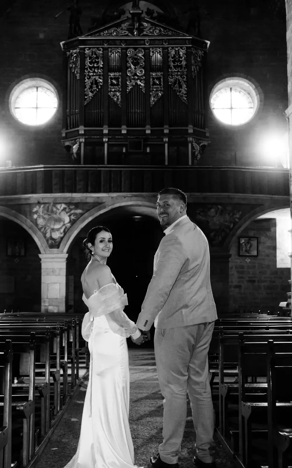 Les mariés main dans la main à la sortie de l'église et danse à la réception, moments clés d'un reportage photo mariage en noir et blanc.