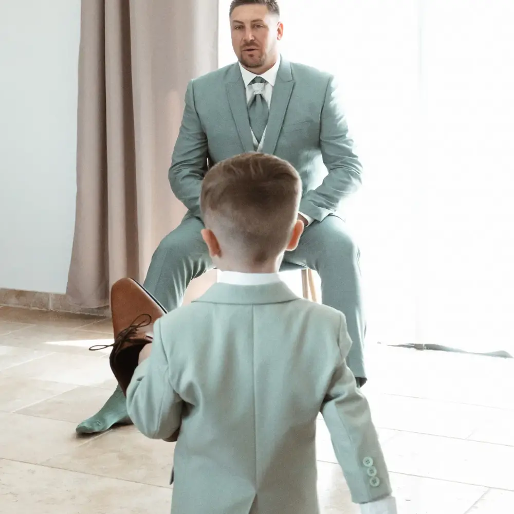 Le marié s'apprête avec un jeune garçon, scène touchante d'un reportage photo vidéo de mariage complet.